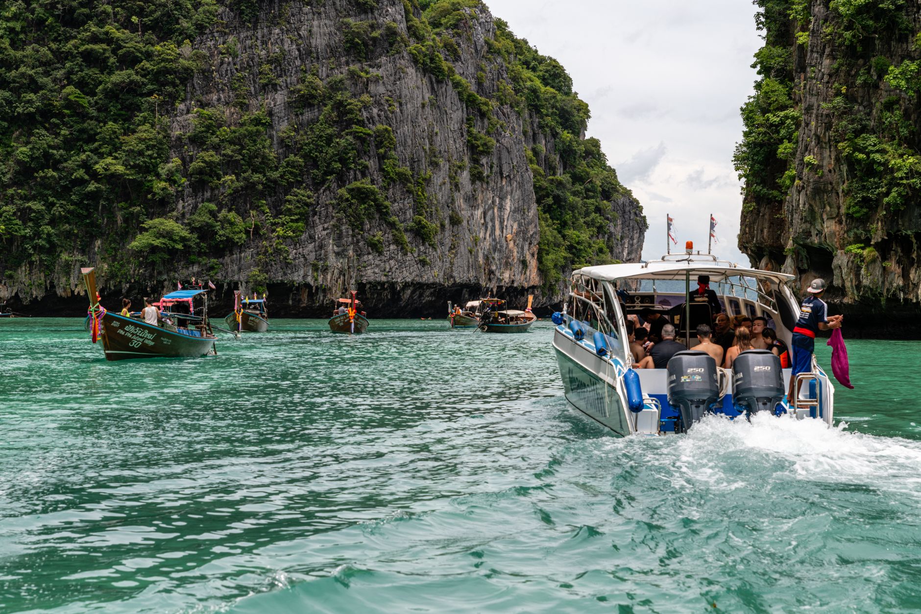 เรือสปีดโบ๊ทจอดใกล้หน้าผาหินปูน นักท่องเที่ยวกำลังขึ้นเรือ