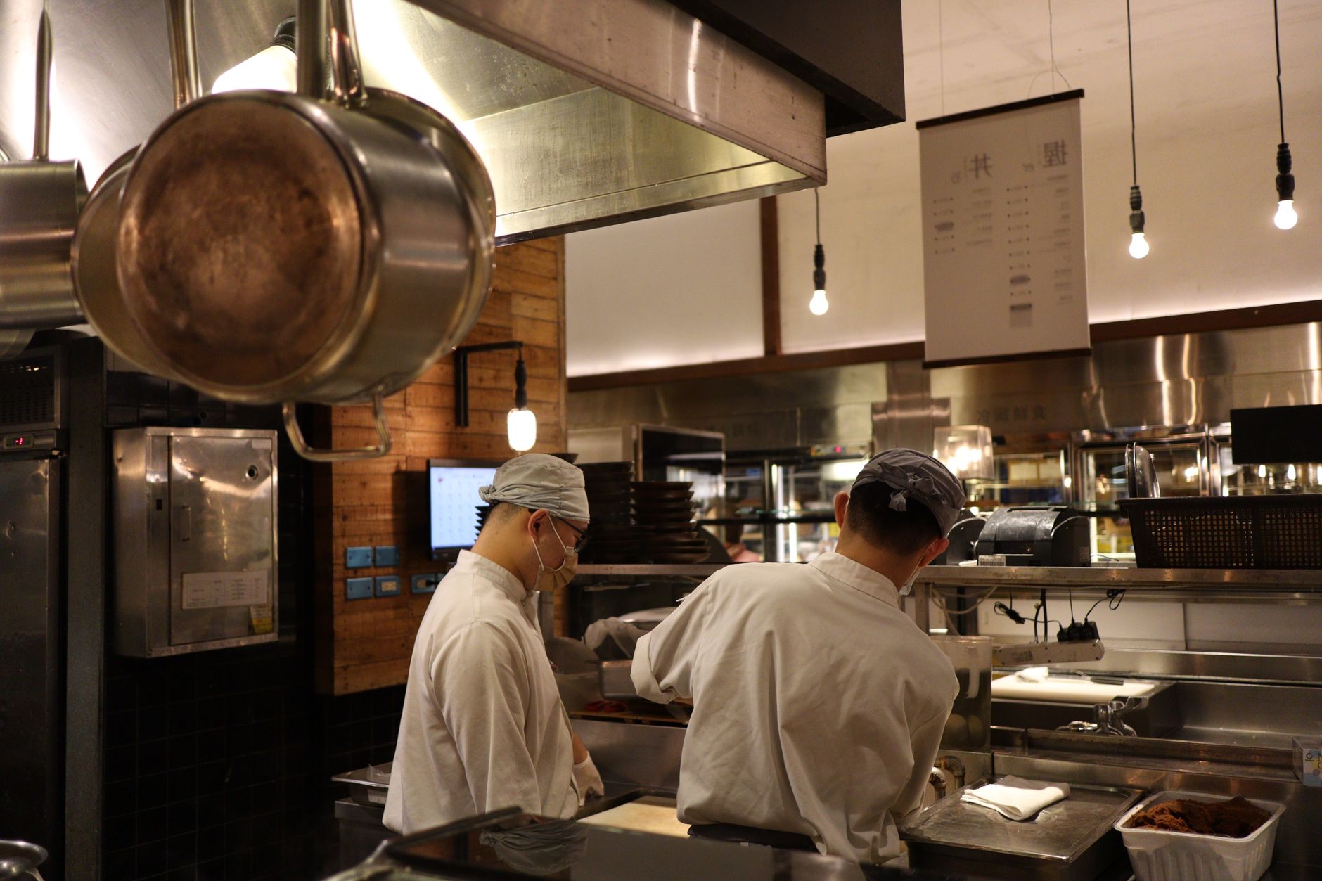 A cook in a busy kitchen filling takeaway containers at the counter