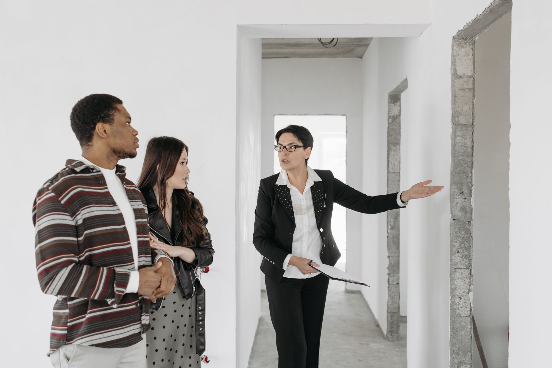 Agent showing a pool villa to a couple holding printed floor plans